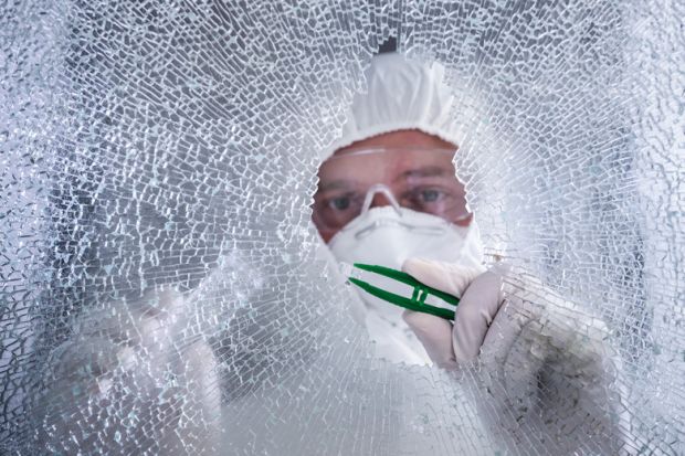 Forensic examiner inspecting broken shatterproof window
