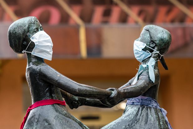 The two female heads of a bronze figure wear a protective face mask on April 3, 2020 in Jena, Germany