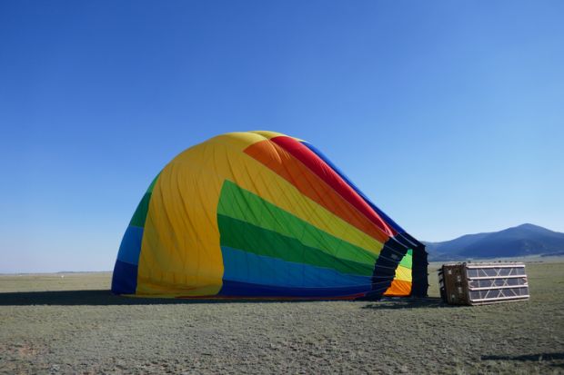 Deflated rainbow colored hot air balloon laying on side Deflated rainbow colored hot air balloon laying on side