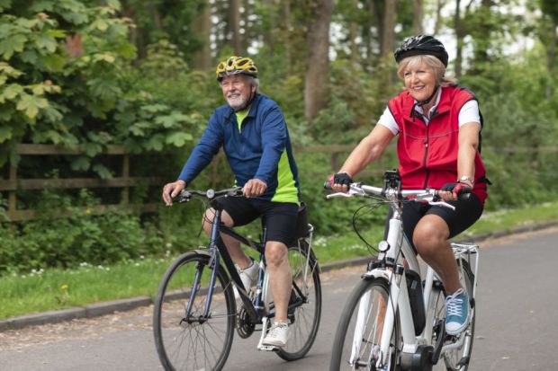 Senior couple wearing sports clothing and cycling helmets on a summers day Senior couple wearing sports clothing and cycling helmets on a summers day