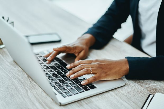 An unrecognisable person using a laptop in an office 