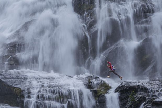 climber jumping between rocks under the "Cascata del Toce" (Toce waterfall), a waterfall in the Italian Alps climber jumping between rocks under the "Cascata del Toce" (Toce waterfall), a waterfall in the Italian Alps