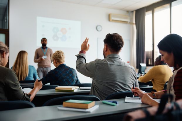 A man raises his hand in a classroom