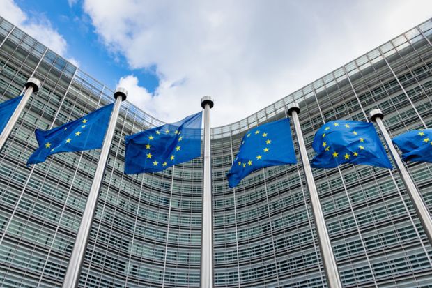 European flags waving in the wind side by side in front of the Berlaymont building facade, headquarters of the European Commission.