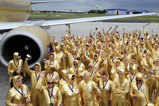 People in gold outfits next to a plane
