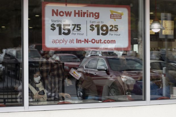 Grants Pass, OR, USA - Mar 19, 2022 Now Hiring sign with promised hourly wage rates is seen at one of the In-N-Out Burger chain restaurants in Grants Pass, Oregon, amidst the labor shortage.