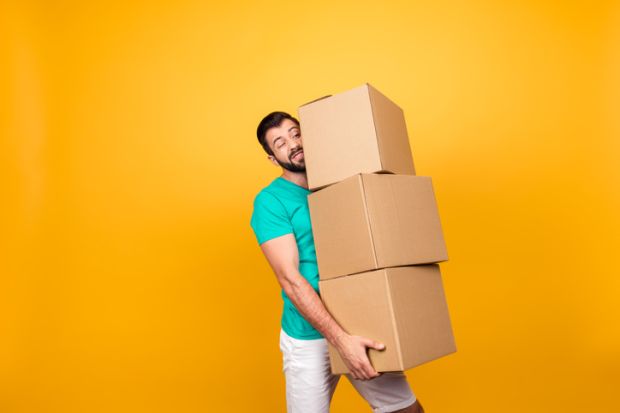 Grimacing courier is trying to keep big stack of cardboard boxes in his hand