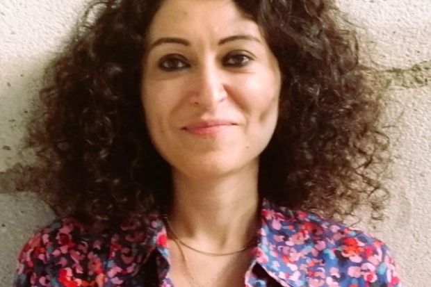 A close-up of Güllistan Yarkin, a woman with short curly hair, smiling at the camera