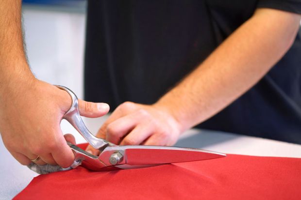 Hand cutting red cloth with scissors