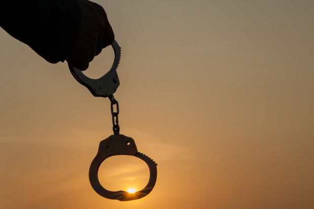 A person holding up handcuffs in the sunrise, symbolising autonomy