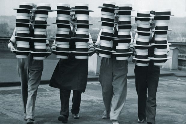 Four people carrying piles of hats