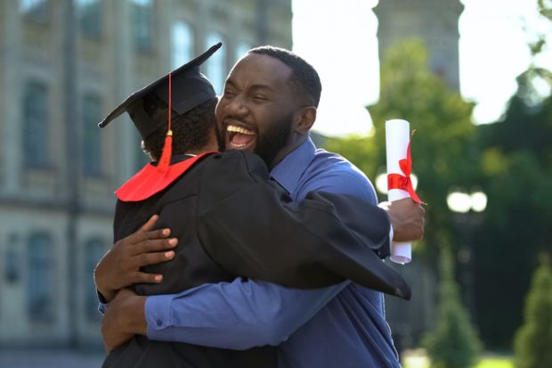 A cheerful father and graduating son hugging