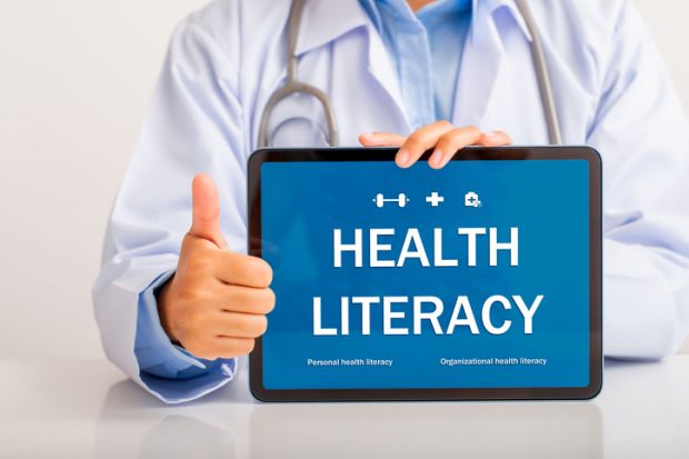 A doctor holding a "health literacy" sign