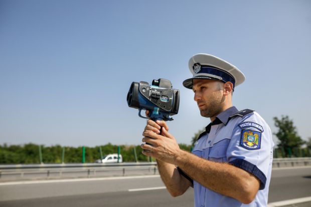 Highway 2 Bucharest - Constanta, Romania - 10 August, 2021 Romanian Road Police officer uses a radar speed gun.