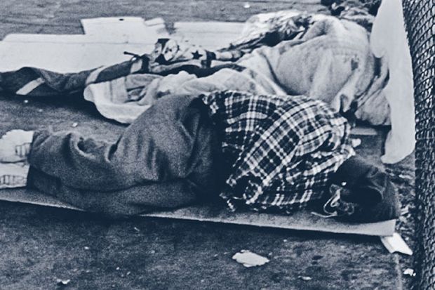 Homeless person asleep on street pavement