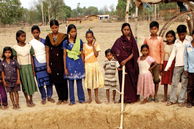 Indian women and children standing beside well