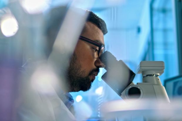 An Indian scientist looks through a microscope