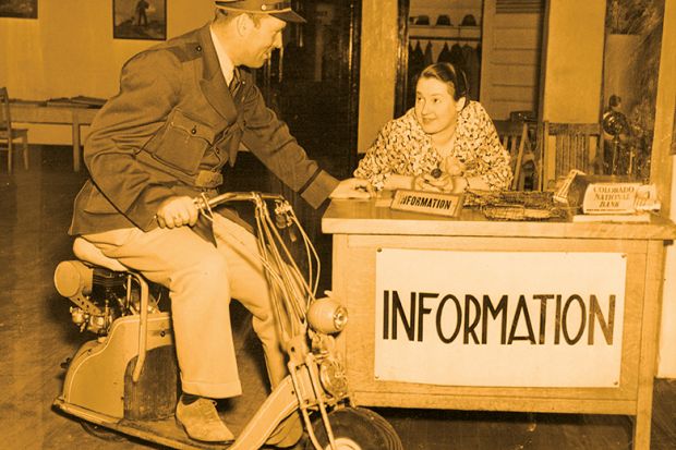 Man on scooter talks to woman at information desk Man on scooter talks to woman at information desk