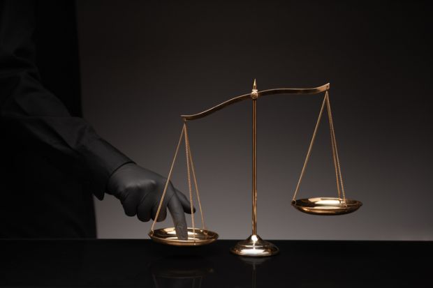 A man presses his finger on the scales of justice