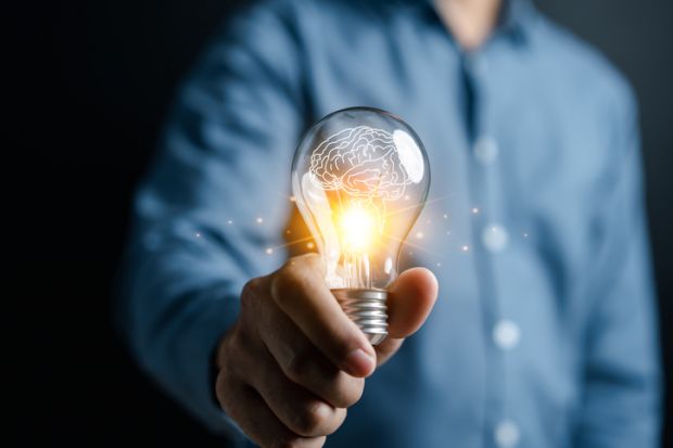 A man offers a lit lightbulb, signifying innovation