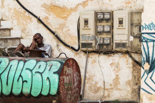 A cuban man sitting on steps with his legs on an oil tank A cuban man sitting on steps with his legs on an oil tank