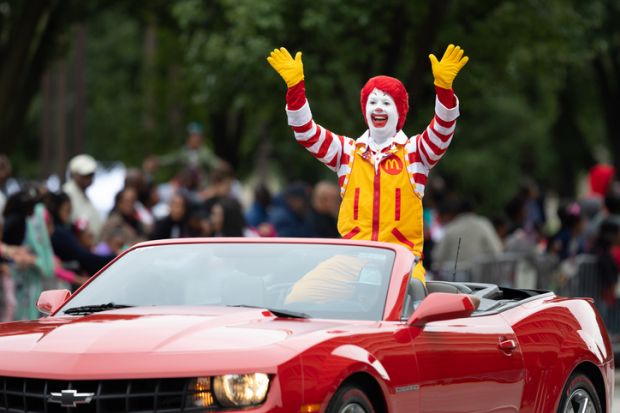 Ronald McDonald waving at spectators while going on a camaro down the road Ronald McDonald waving at spectators while going on a camaro down the road