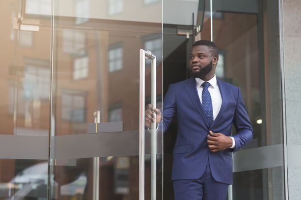 Businessman in formal suit walking out of modern office