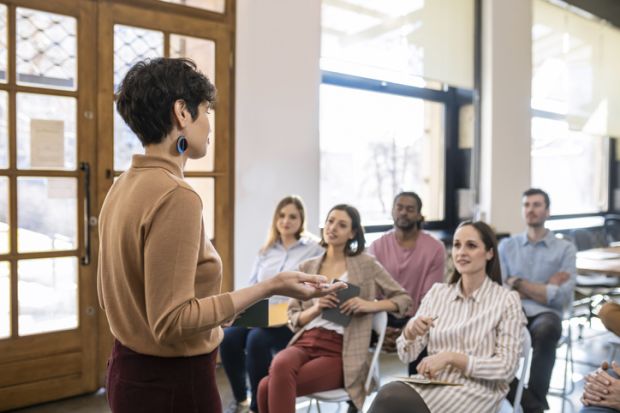 A woman giving a university lecture to several students
