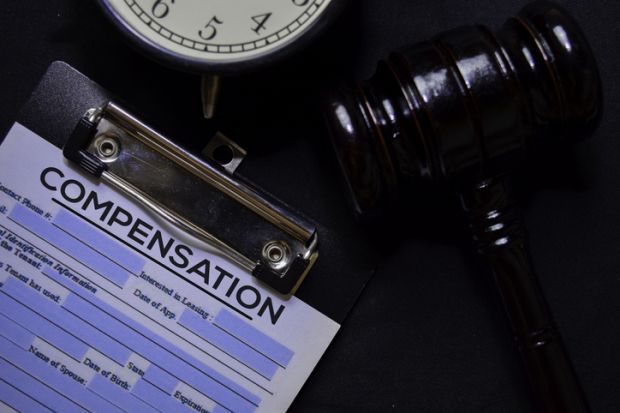 Paperwork for a compensation claim sits on a desk with a gavel