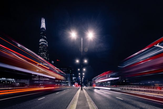 Blurred cars speed down a city street at night