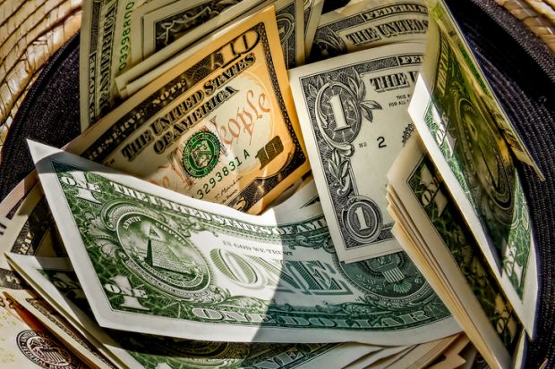 Straw hat with a stack of dollar bills inside Straw hat with a stack of dollar bills inside