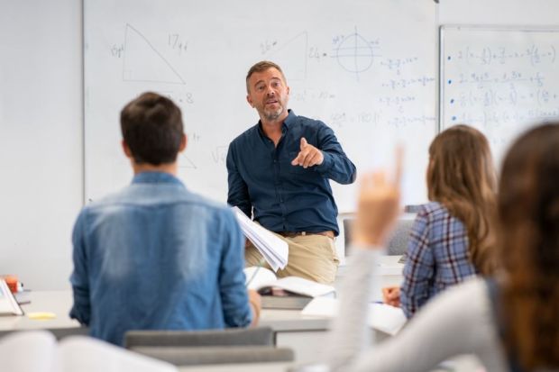 Professor pointing at college student with hand raised in classroom