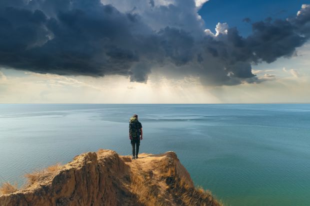 A man stands on the edge of a cliff