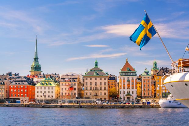 The Stockholm skyline with a flag of Sweden perched on a boat