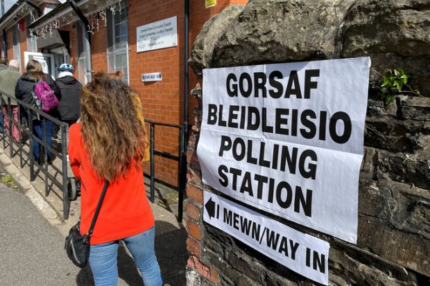 Queue of people waiting to enter a polling station in a village hall