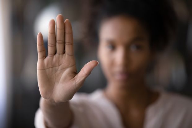 A woman holds her hand up in front of her to signal 'no'