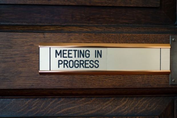 Sign on door saying 'Meeting in progress' Close-up of sign on door saying 'Meeting in progress'