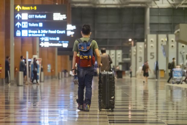  A man wheels a suitcase towards check-in counters at the departure hall of Terminal 3, Changi Airport.