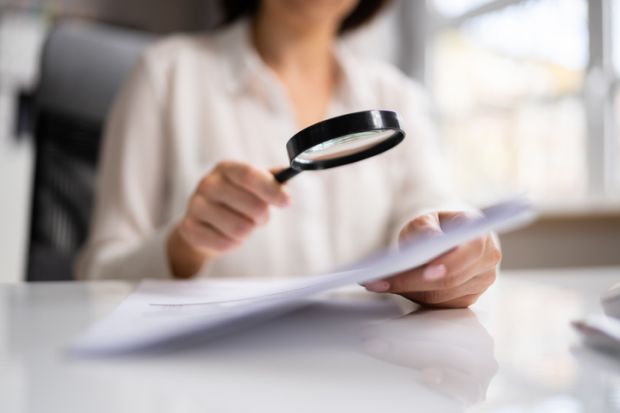 Woman looks at document with magnifying glass