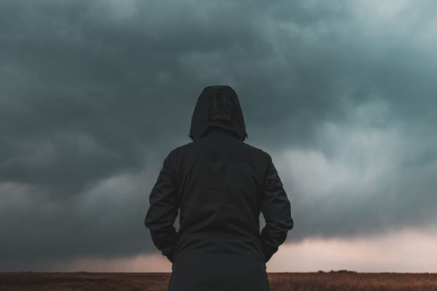 A person with their back to the camera looks at a big grey cloud A person with their back to the camera looks at a big grey cloud