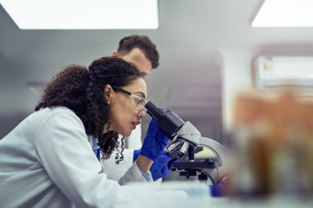 A woman looking at test sample through a microscope in laboratory