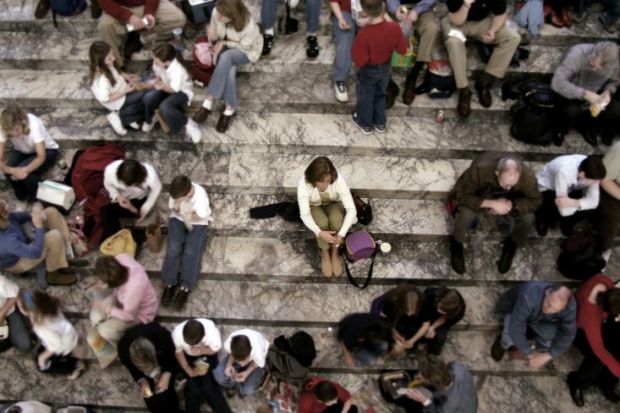 Woman sits alone on steps with everyone else in groups
