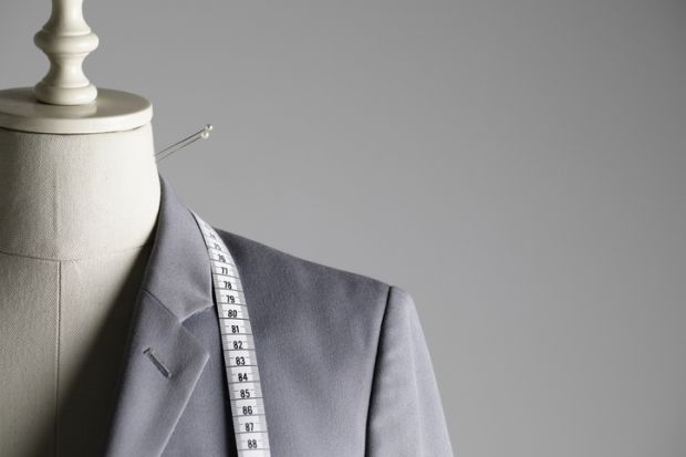 Suit jacket on tailor's mannequin with pins and tape measure