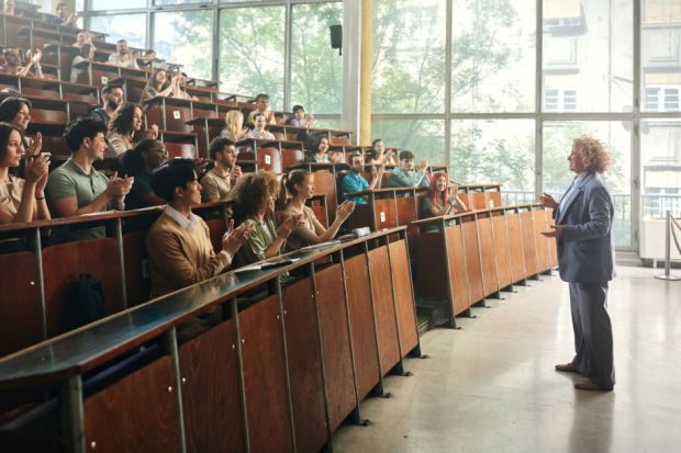 Dozens of students in a lecture hall applauding to their professor
