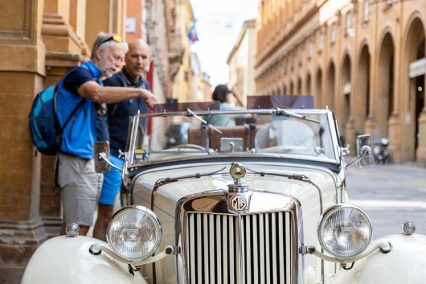 Two men admiring an MG T-Series car parked in the city centre in Bologna