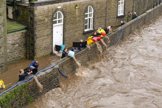 People tipping floodwater out of the basement level of Pontypridd town museum in south Wales