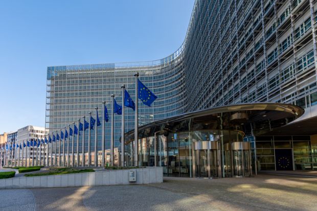 Entrance to the Berlaymont building, headquarters of the European Commission, with several EU flags lining the edge