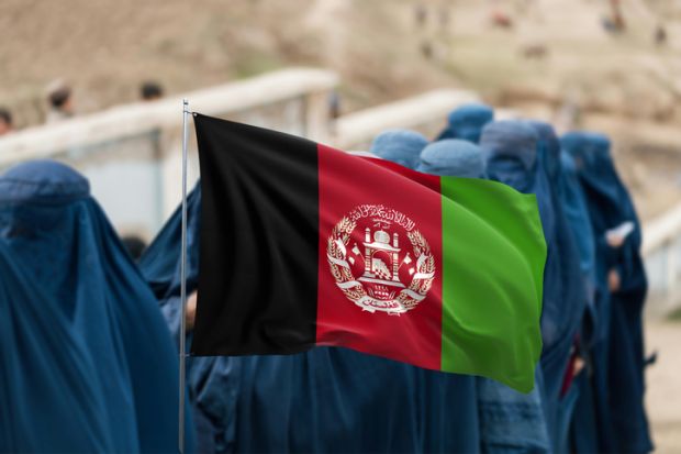 Afghan flag displayed over group of women wearing burqas 