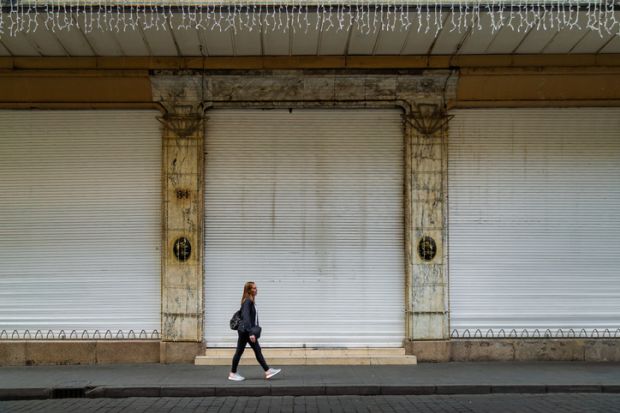 Woman walking past a closed storefront on a street in the historic center of Mexico City