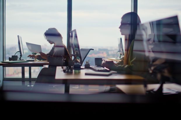 Busy corporate office silhouettes at cityscape window